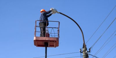 electrician climb work installing new street lamp on electricity power concrete pole in blue sky